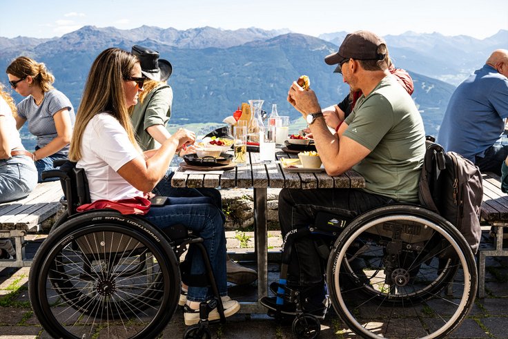 Personen mit Rollstuhl am Tisch bei Außenbereich von Bergrestaurant