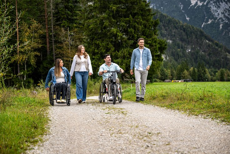 Rollstuhlfahrere bei Ausflug in der Natur auf Schotterstraße