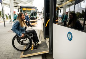 Rollstuhlfahrererin fährt über Rampe in Bus