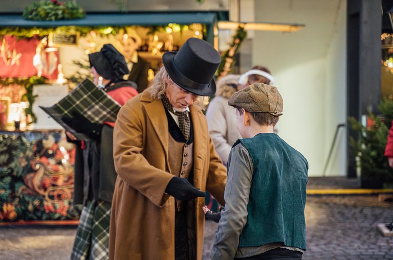 Viktorianisch gekleidetet Manmit Kind am Weihnachtsmarkt